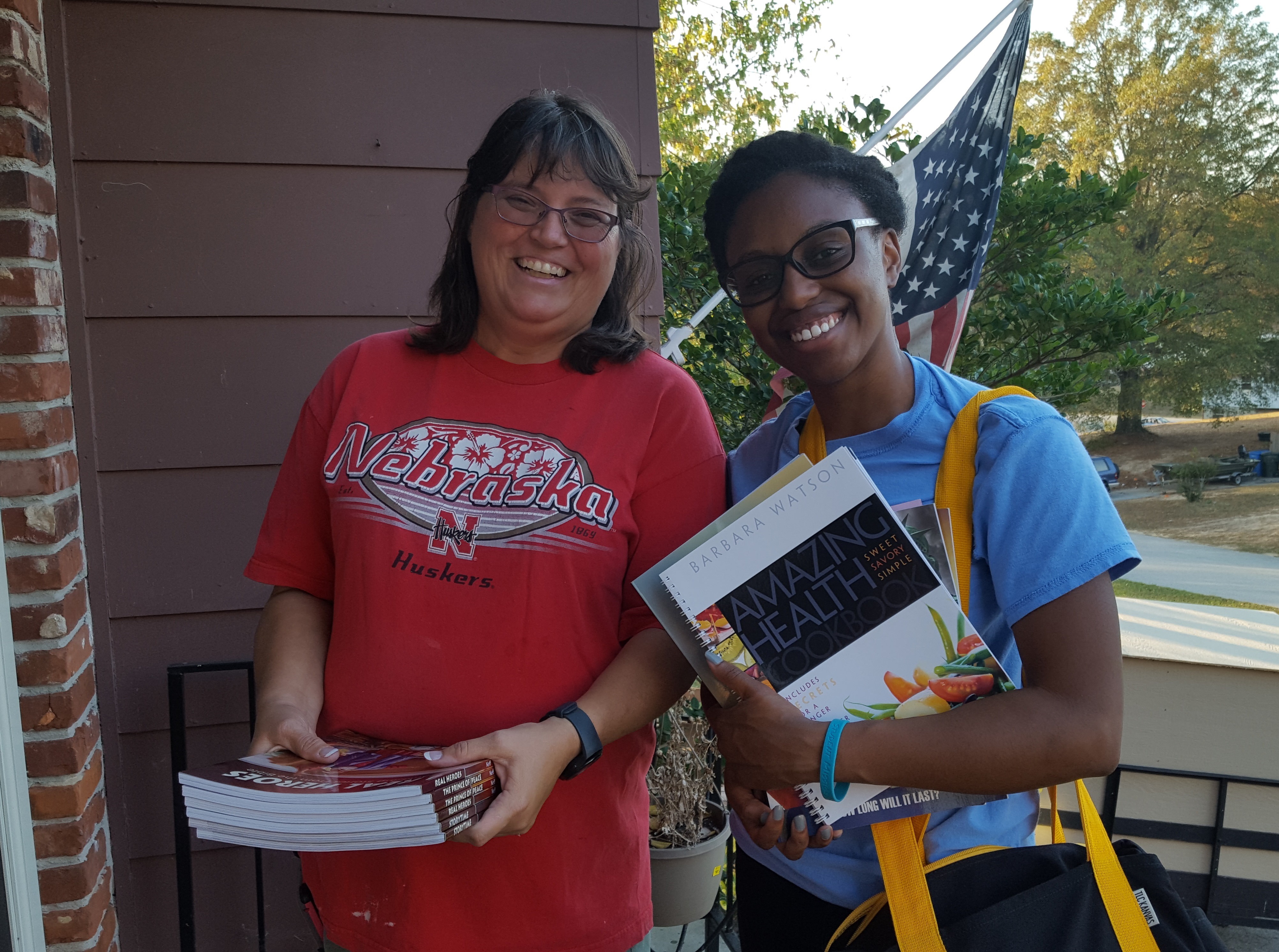 Two people smiling, holding books