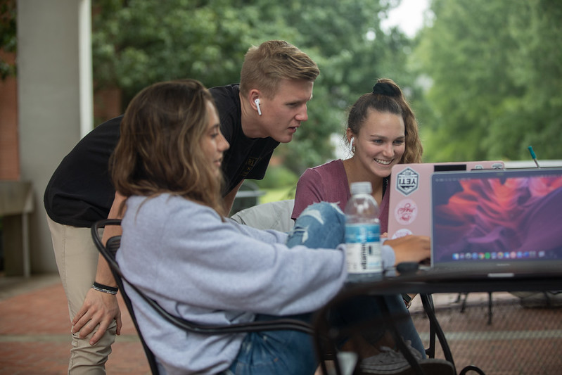 Student helping another on a computer